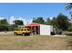 A red and white outbuilding is next to a bright yellow SUV and a motorcycle on a paved pad at 28024 Cleveland Ave, Punta Gorda, FL 33982