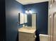 Bathroom with navy walls boasts a modern vanity with a framed mirror and wall sconces at 3300 Loveland Blvd # 602, Punta Gorda, FL 33980