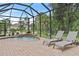 Enclosed pool area with two lounge chairs, patio, and tropical plants near a waterfall feature at 3393 S Haberland Blvd, North Port, FL 34288