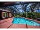Bright pool in a screened enclosure with tile decking, and surrounding landscaping at 3960 Magara Ter, North Port, FL 34287