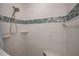 Close-up of the new shower with white tile, blue accents, and convenient shelving at 3960 Magara Ter, North Port, FL 34287