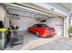 Garage with a red convertible parked inside, showcasing ample space and additional storage on shelving at 43249 Treadway Dr, Punta Gorda, FL 33982