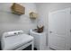 Bright laundry room with white appliances, wire shelving, and a woven basket for organized storage solutions at 43249 Treadway Dr, Punta Gorda, FL 33982