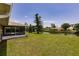 Beautiful waterfront backyard featuring a large lawn, mature tree, and screened-in lanai at 444 Edgewood Rd, Venice, FL 34293