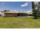 Lovely backyard with a screened-in lanai, lush lawn, and mature tree on a sunny day at 444 Edgewood Rd, Venice, FL 34293