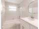 Bright bathroom features a tub, shower, and white vanity with sleek fixtures and a decorative circular mirror at 444 Edgewood Rd, Venice, FL 34293