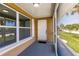 View of the covered front porch showing the front door, screen enclosure, and landscaping at 444 Edgewood Rd, Venice, FL 34293