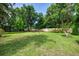 Expansive backyard with vibrant green lawn, mature trees, wooden swing, and a serene, park-like setting at 4511 Wilkinson Rd, Sarasota, FL 34233
