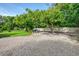 Spacious gravel backyard with mature trees and landscaping offering a versatile outdoor space at 4511 Wilkinson Rd, Sarasota, FL 34233