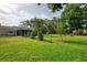 Lush, green backyard featuring a screened patio, mature trees, and ample space for outdoor activities and relaxation at 4511 Wilkinson Rd, Sarasota, FL 34233