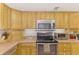 Detailed view of the kitchen showing stainless steel oven, microwave, and light wood cabinets at 4511 Wilkinson Rd, Sarasota, FL 34233