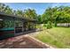 Relaxing screened patio with brick floors offering a peaceful view of the lush backyard and pool area at 4511 Wilkinson Rd, Sarasota, FL 34233