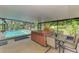 Covered patio featuring a hot tub, outdoor dining area, and a view of the sparkling screened-in pool and lush greenery at 4511 Wilkinson Rd, Sarasota, FL 34233