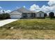 Charming single-story home featuring a lush green lawn, a two car garage, and a beautifully landscaped front yard at 9469 Spring Cir, Port Charlotte, FL 33981