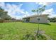 A view of the grassy backyard and back side of the house from a far distance on a sunny day at 1057 Presque Isle Dr, Port Charlotte, FL 33952
