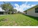 Large grassy backyard with fencing, trees, and the home's exterior at 1057 Presque Isle Dr, Port Charlotte, FL 33952