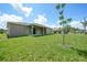 A view of the grassy backyard, the covered patio, and partial view of the house on a sunny day at 1057 Presque Isle Dr, Port Charlotte, FL 33952