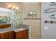 Well-lit bathroom featuring a granite countertop, wood cabinets, and tiled shower with an arched window at 13471 Chenille Dr, Port Charlotte, FL 33981