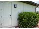 Side exterior door with a modern light fixture and verdant landscaping for added privacy at 13471 Chenille Dr, Port Charlotte, FL 33981