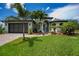 Charming home with a well-manicured lawn, brick driveway, and tropical landscaping at 13471 Chenille Dr, Port Charlotte, FL 33981