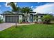 Charming home with a well-manicured lawn, brick driveway, and tropical landscaping at 13471 Chenille Dr, Port Charlotte, FL 33981