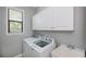 Bright laundry room features a utility sink, storage cabinets, and a washer/dryer, offering practical convenience at 13471 Chenille Dr, Port Charlotte, FL 33981