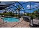 Screened-in pool area with a hot tub, table set, brick pavers, and a view of the canal at 13471 Chenille Dr, Port Charlotte, FL 33981