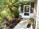 Front porch with blooming flowers, a palm tree, and a paved walkway leading to the entrance at 1431 Red Oak Ln, Port Charlotte, FL 33948