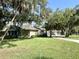 Street view of charming homes with well-kept lawns and landscaping, shaded by mature trees at 1431 Red Oak Ln, Port Charlotte, FL 33948