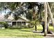 Charming home showcasing a screened porch, vibrant landscaping, and mature trees in a verdant lawn at 1431 Red Oak Ln, Port Charlotte, FL 33948
