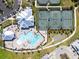 Aerial view of resort-style pool, clubhouse, tennis courts, and lush landscaping at 15039 Black Cherry Way, Punta Gorda, FL 33955