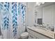 Well-lit bathroom featuring a shower with a decorative blue curtain and a granite countertop at 15039 Black Cherry Way, Punta Gorda, FL 33955