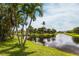 Picturesque waterfront backyard with palm trees and manicured lawn, offering serene views of the canal and surrounding landscape at 17150 Sarong Ln, Punta Gorda, FL 33955