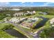 Aerial view of the community with a pool, tennis courts, and parking, nestled among trees and a pond at 175 Kings Hwy # 625, Punta Gorda, FL 33983