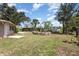 Large backyard features mature trees, grass, and a stone-lined garden bed at 18178 Wolbrette Cir, Port Charlotte, FL 33948
