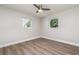 Bright bedroom features a ceiling fan, wood-look floors, and two windows letting in natural light at 18178 Wolbrette Cir, Port Charlotte, FL 33948