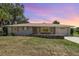 Charming single-story home with a well-maintained lawn and rock border at sunset at 18178 Wolbrette Cir, Port Charlotte, FL 33948