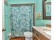 Well-lit bathroom with blue-green walls, a shower with a patterned curtain, and a modern vanity at 2031 Backton St, Port Charlotte, FL 33948