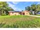 Charming single-story home with an orange exterior, well-manicured lawn, solar panels, and mature trees at 2031 Backton St, Port Charlotte, FL 33948