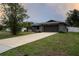 Charming one-story home with a spacious concrete driveway, lush lawn, and gray exterior at 21220 Pemberton Ave, Port Charlotte, FL 33952