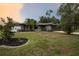 Charming one-story home with mature landscaping, featuring a well-maintained lawn and palm trees at 21220 Pemberton Ave, Port Charlotte, FL 33952