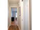 Hallway with wood floors leading to bedroom featuring a black dresser, and a window with blinds at 21220 Pemberton Ave, Port Charlotte, FL 33952