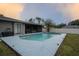 Backyard pool with screened in porch, surrounded by a concrete deck and green lawn at 21220 Pemberton Ave, Port Charlotte, FL 33952