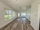 Bright living room showcasing wood-look flooring and ample natural light from expansive windows at 21899 Cellini Ave, Port Charlotte, FL 33952