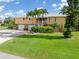 Spacious two-story home boasting a two-car garage and lush green lawn, enhanced by mature palm trees at 24398 Treasure Island Blvd, Punta Gorda, FL 33955