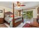 Bedroom with four-poster bed, tiled floor, ceiling fan, and sliding doors to balcony at 24398 Treasure Island Blvd, Punta Gorda, FL 33955