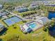 An aerial view of community amenities: swimming pool, tennis courts, clubhouse, and surrounding colorful condo buildings at 25555 Heritage Lake Blvd # 27, Punta Gorda, FL 33983