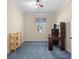 Bedroom with blue carpet, ceiling fan, and a large desk setup with natural light streaming through a window at 25555 Heritage Lake Blvd # 27, Punta Gorda, FL 33983