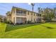A yellow two-story condo building with a well-maintained lawn, mature landscaping, and a screened-in patio at 25555 Heritage Lake Blvd # 27, Punta Gorda, FL 33983