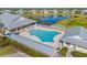 Aerial view showcasing the community pool, sundeck with lounge chairs, clubhouse and a scenic pond at 25555 Heritage Lake Blvd # 27, Punta Gorda, FL 33983